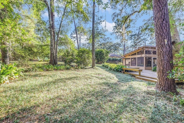 view of yard featuring a sunroom and a wooden deck