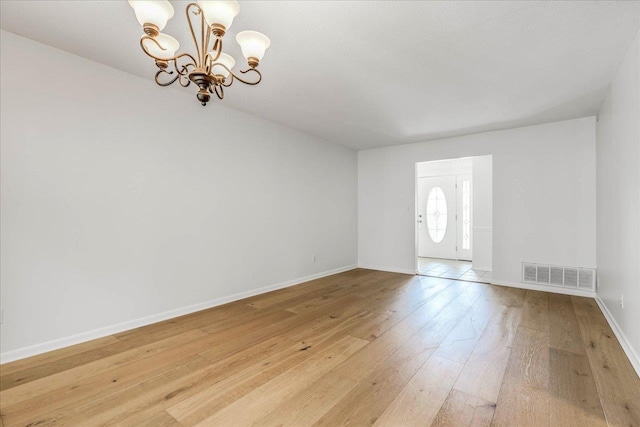 foyer featuring a chandelier, visible vents, light wood-style floors, and baseboards