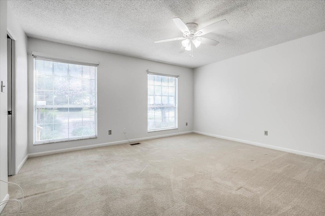 carpeted spare room with visible vents, ceiling fan, a textured ceiling, and baseboards