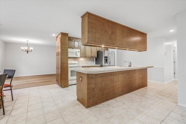 kitchen featuring white appliances, baseboards, decorative backsplash, light countertops, and a notable chandelier