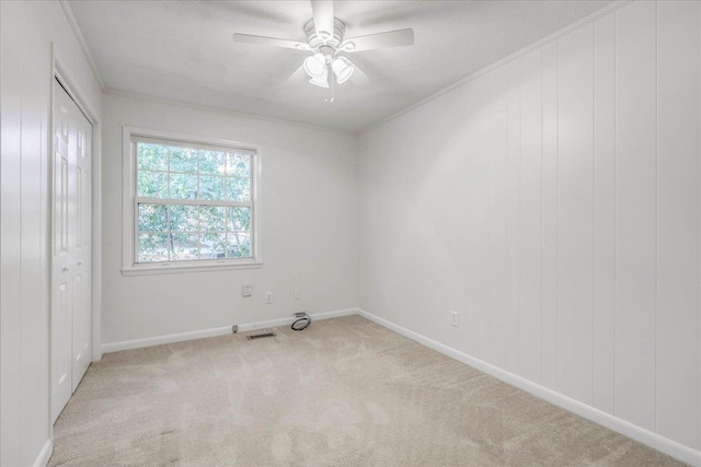 unfurnished room with a ceiling fan, carpet flooring, visible vents, and crown molding