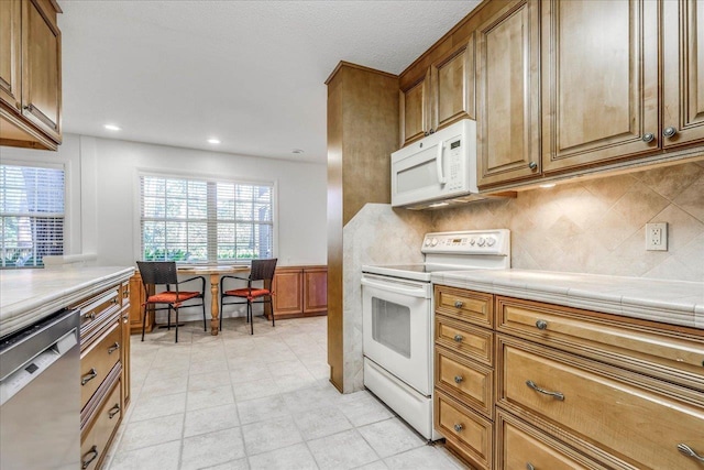 kitchen with white appliances, brown cabinetry, and backsplash