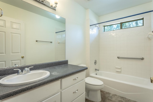 full bathroom with tiled shower / bath, vanity, and toilet