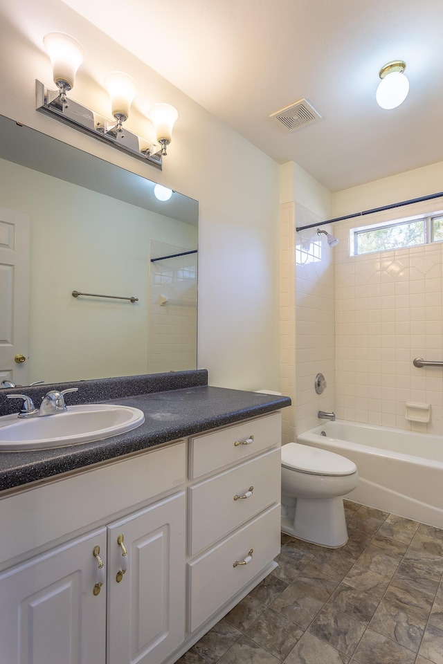 full bathroom featuring tiled shower / bath combo, vanity, and toilet