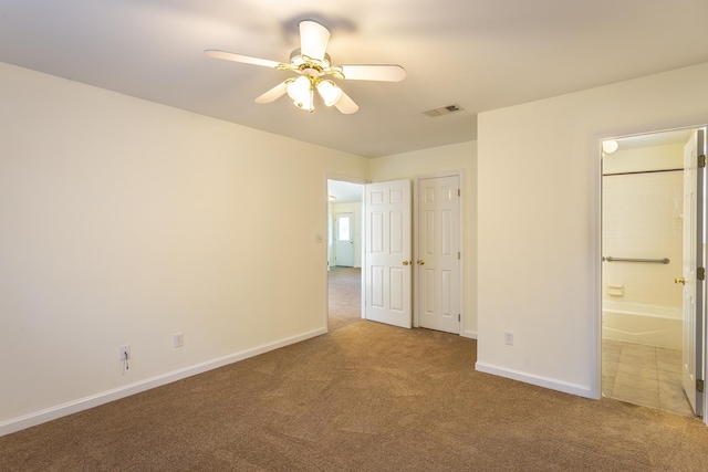 unfurnished bedroom featuring ensuite bath, a closet, ceiling fan, and carpet flooring