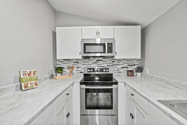 kitchen featuring white cabinetry, appliances with stainless steel finishes, vaulted ceiling, and backsplash