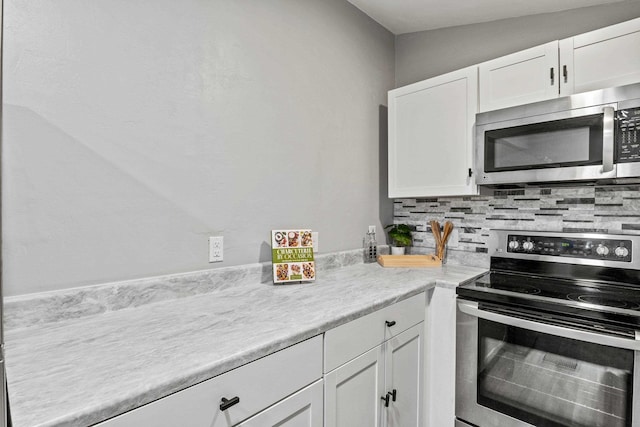 kitchen with white cabinetry, lofted ceiling, stainless steel appliances, and tasteful backsplash