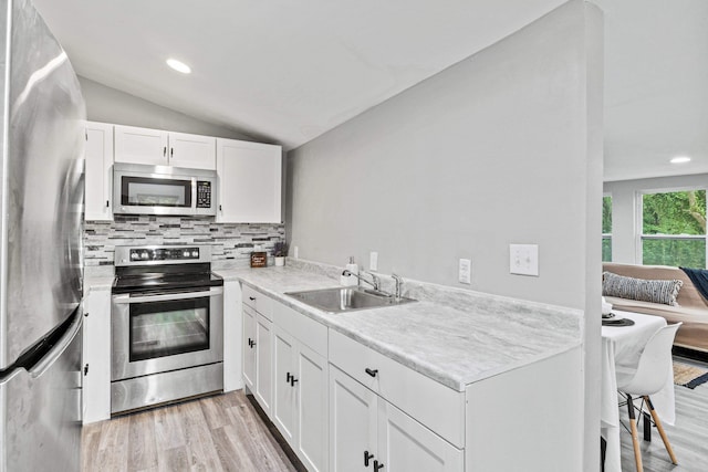 kitchen featuring sink, white cabinetry, vaulted ceiling, light wood-type flooring, and stainless steel appliances