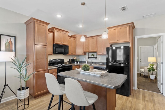 kitchen featuring light hardwood / wood-style flooring, decorative light fixtures, a kitchen island, and black appliances