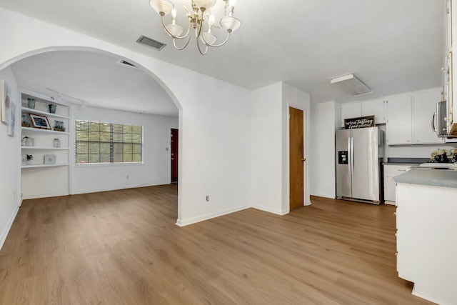 kitchen with white cabinetry, light wood-type flooring, appliances with stainless steel finishes, and a notable chandelier