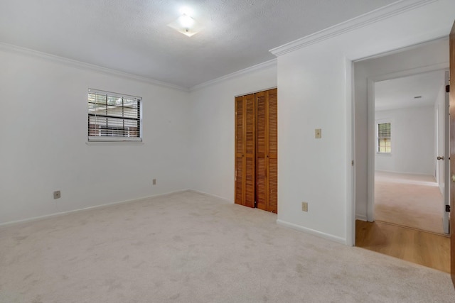 spare room with a textured ceiling, light carpet, and ornamental molding