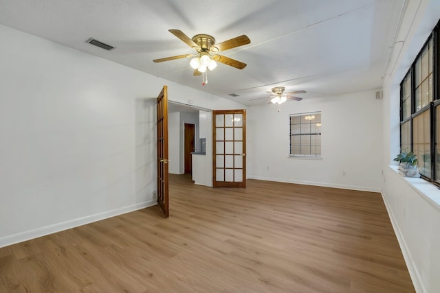 spare room with light wood-type flooring, ceiling fan, and a healthy amount of sunlight