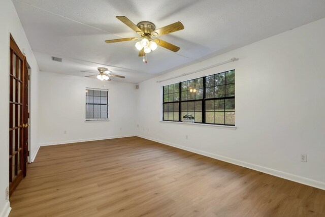 empty room featuring a textured ceiling, light hardwood / wood-style floors, and ceiling fan