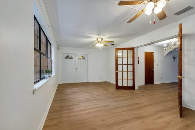 empty room featuring ceiling fan with notable chandelier and light hardwood / wood-style floors