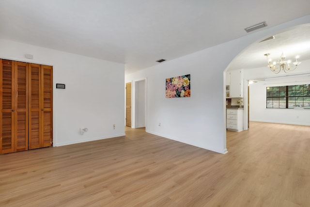 spare room featuring an inviting chandelier and light hardwood / wood-style flooring