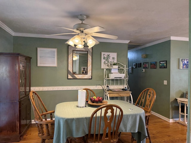 dining space featuring baseboards, a ceiling fan, wood finished floors, and crown molding