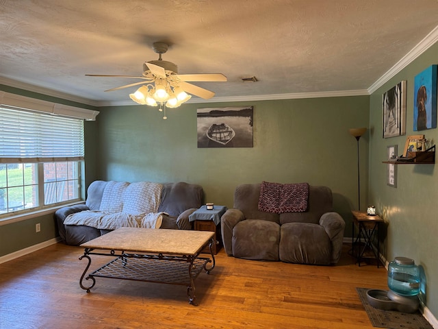 living area with visible vents, ornamental molding, a textured ceiling, wood finished floors, and baseboards