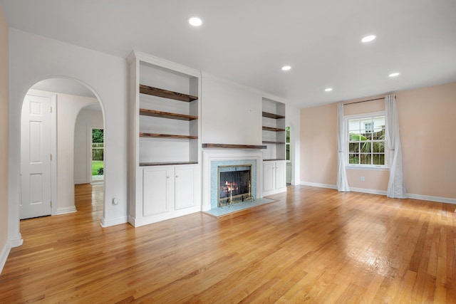 1310 E 7th Ave, Tallahassee, FL 32303 - unfurnished living room featuring baseboards, light wood-type flooring, a lit fireplace, recessed lighting, and built in shelves