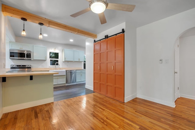 1310 E 7th Ave, Tallahassee, FL 32303 - kitchen featuring stainless steel appliances, light wood-style floors, arched walkways, beamed ceiling, and light countertops