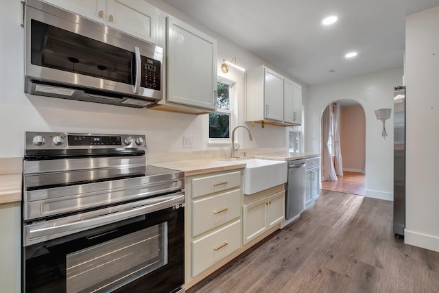 1310 E 7th Ave, Tallahassee, FL 32303 - kitchen featuring stainless steel appliances, arched walkways, a sink, wood finished floors, and recessed lighting