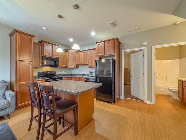 2027 Ann Arbor Ave Unit 1501, Tallahassee, FL 32304 - kitchen with black appliances, a sink, light wood-style floors, a kitchen island, and a kitchen bar