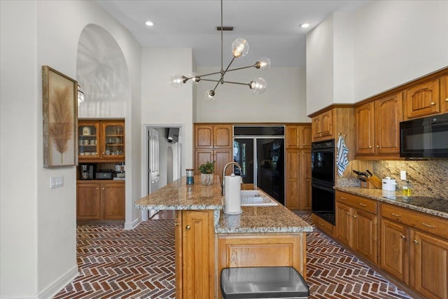 411 Worley Way, Perry, FL 32347 - kitchen with brick flooring, black appliances, a high ceiling, light stone countertops, and decorative backsplash