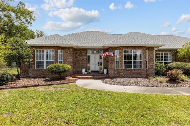 411 Worley Way, Perry, FL 32347 - view of front of house with a front yard, a shingled roof, and brick siding