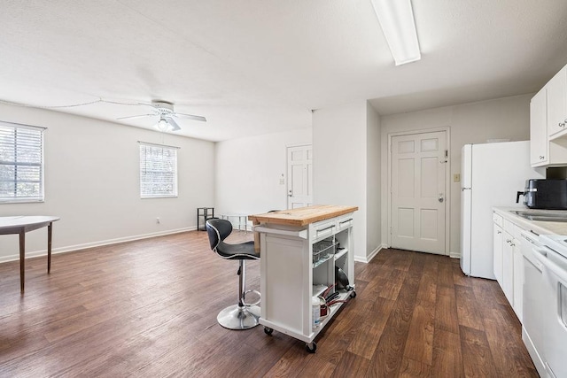 kitchen with butcher block countertops, a breakfast bar area, white cabinets, dark hardwood / wood-style flooring, and stove