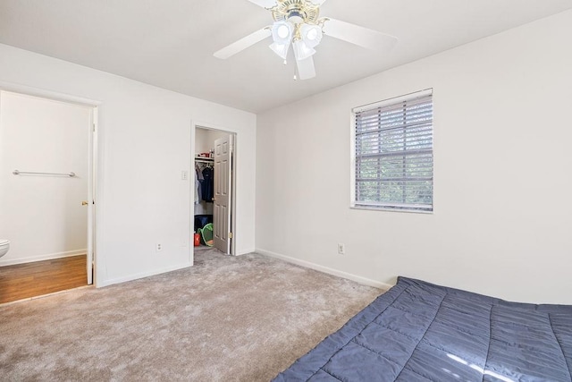 unfurnished bedroom with ceiling fan, a spacious closet, a closet, and carpet