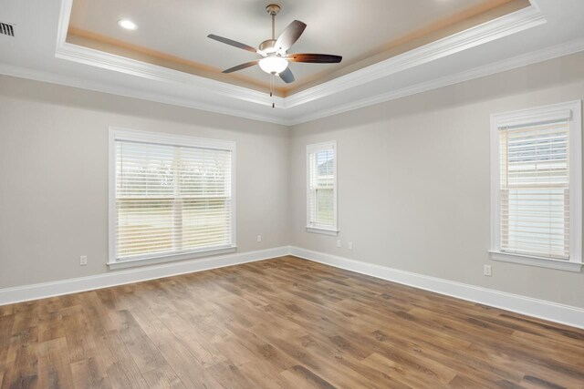 spare room featuring crown molding, wood-type flooring, and a raised ceiling