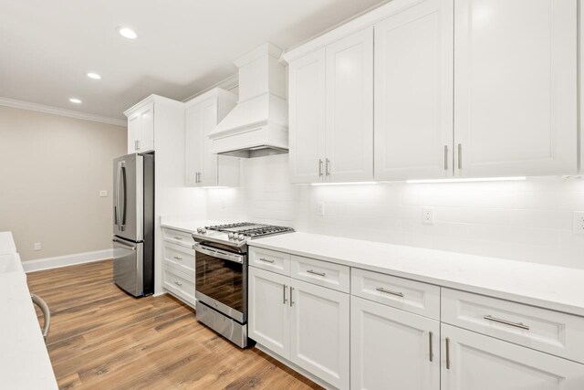 kitchen with white cabinetry, stainless steel appliances, and premium range hood