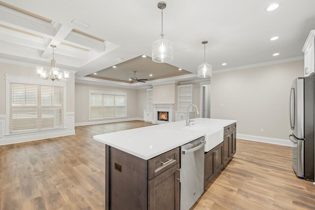 kitchen with sink, appliances with stainless steel finishes, decorative light fixtures, dark brown cabinets, and light wood-type flooring