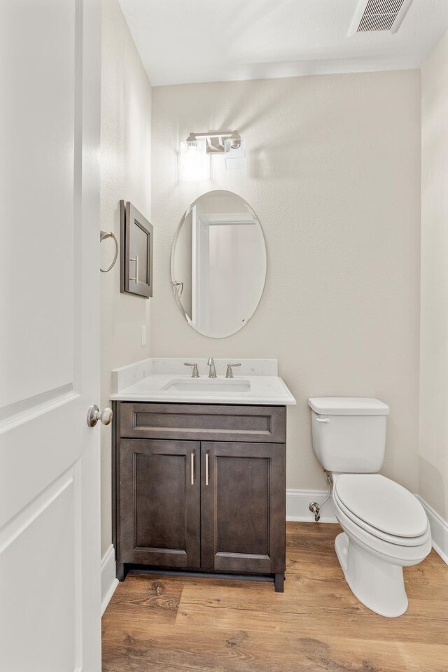 bathroom featuring toilet, vanity, and hardwood / wood-style floors