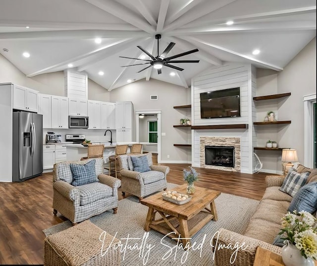 living room with dark wood-type flooring, sink, beamed ceiling, ceiling fan, and a fireplace