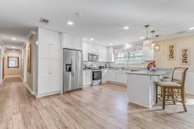 kitchen with white cabinetry, stainless steel appliances, a kitchen breakfast bar, light stone countertops, and decorative light fixtures