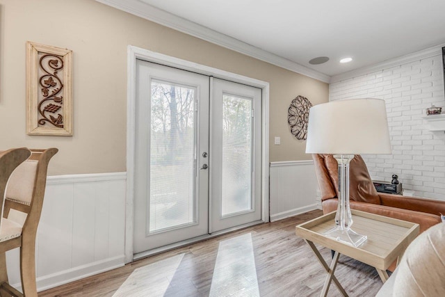 doorway with french doors, brick wall, ornamental molding, and light wood-type flooring