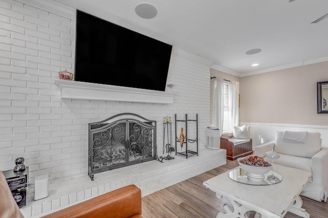 living room with ornamental molding, hardwood / wood-style floors, and a brick fireplace