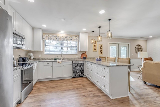 kitchen featuring a breakfast bar, hanging light fixtures, appliances with stainless steel finishes, kitchen peninsula, and white cabinets