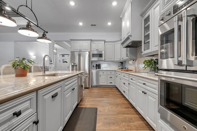 kitchen featuring sink, appliances with stainless steel finishes, white cabinetry, light stone counters, and tasteful backsplash