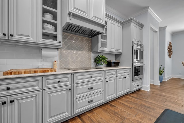 kitchen featuring dark wood-type flooring, custom exhaust hood, crown molding, black electric cooktop, and stainless steel double oven