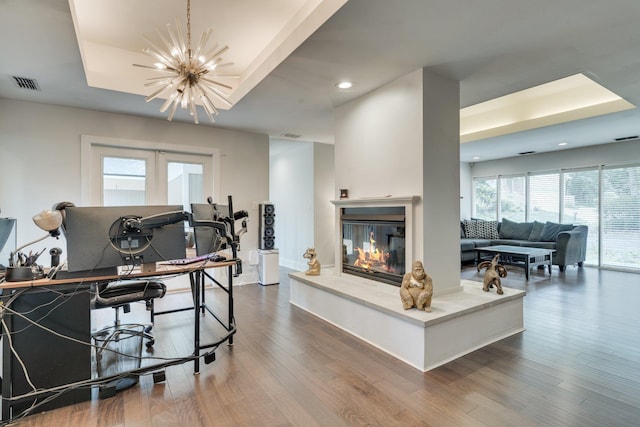 2414 Glenshire Ln, Tallahassee, FL 32308 - living room featuring wood finished floors, a chandelier, recessed lighting, a tray ceiling, and a glass covered fireplace