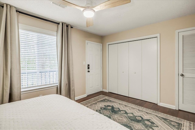 bedroom featuring ceiling fan, dark wood-type flooring, and a textured ceiling