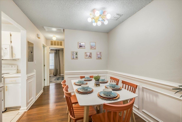 dining area featuring electric panel, a textured ceiling, and hardwood / wood-style flooring