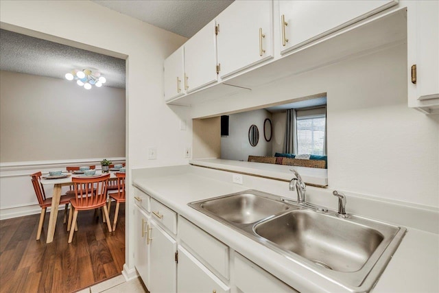 kitchen with sink, hardwood / wood-style flooring, white cabinets, and a textured ceiling