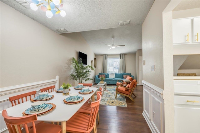 dining room with a textured ceiling, dark wood-type flooring, and ceiling fan with notable chandelier