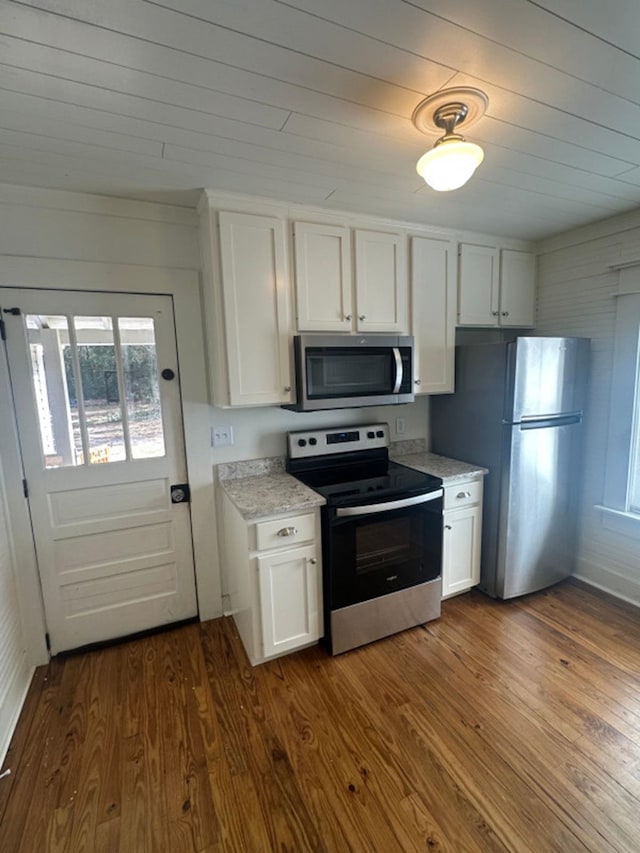 kitchen with white cabinets, stainless steel appliances, dark wood-type flooring, and light stone countertops