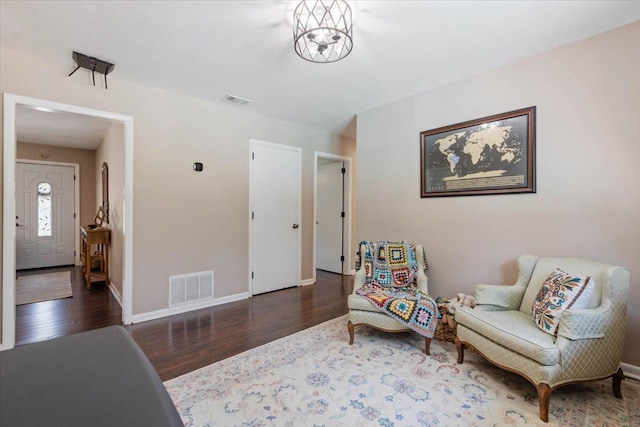 living area featuring visible vents, baseboards, an inviting chandelier, and wood finished floors