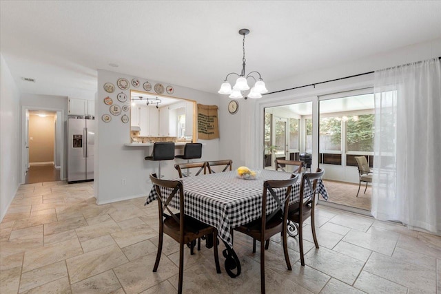 dining space with stone tile flooring, visible vents, a notable chandelier, and baseboards