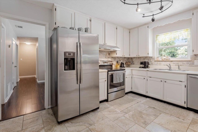 kitchen featuring a sink, stainless steel appliances, tasteful backsplash, and under cabinet range hood