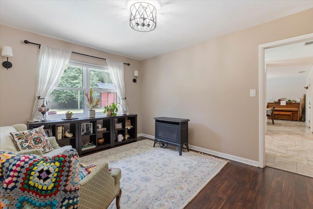 living room featuring visible vents, a wood stove, wood finished floors, and baseboards